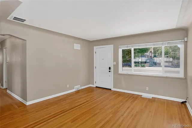 a view of an empty room with wooden floor and a window