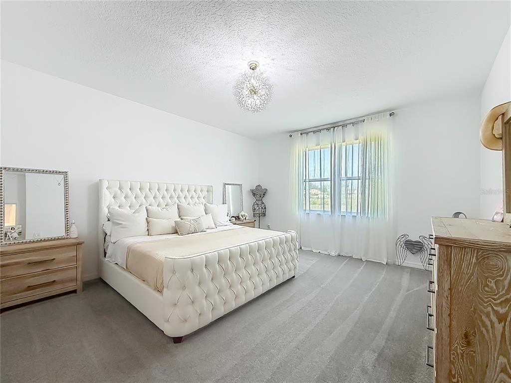7429 Southwest 61st Street Ocala, FL 34474 - Photo 14 of 40 a bedroom with a bed and a chandelier