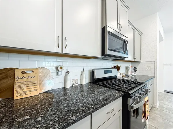 a kitchen with granite countertop a sink a stove and cabinets