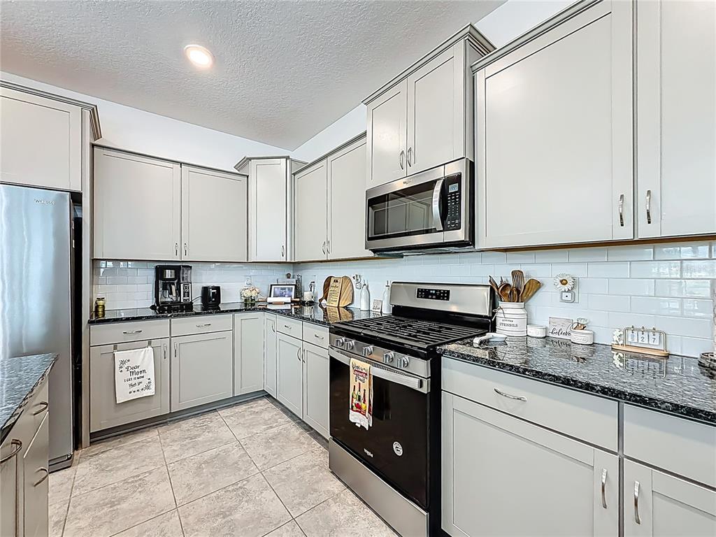 7429 Southwest 61st Street Ocala, FL 34474 - Photo 5 of 40 a kitchen with stainless steel appliances granite countertop a stove top oven a refrigerator a sink and white cabinets