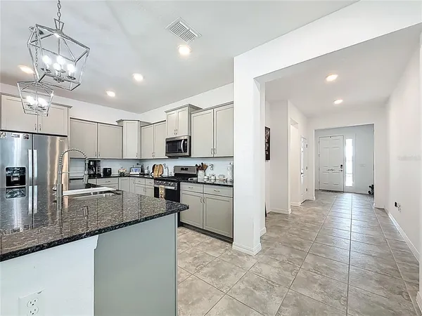 a kitchen with stainless steel appliances granite countertop a refrigerator a sink dishwasher a stove and white cabinets with wooden floor