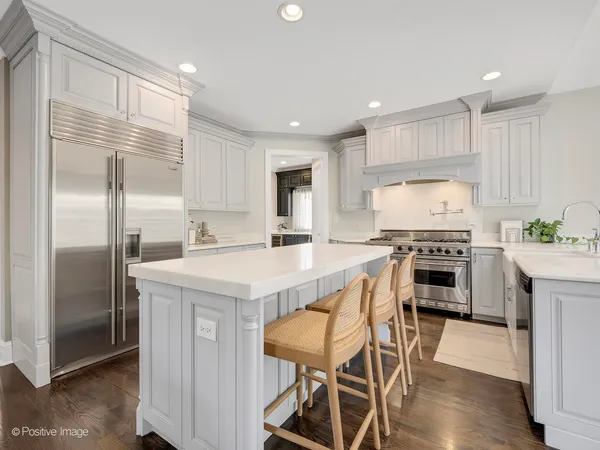 a kitchen with kitchen island granite countertop a stove a refrigerator a oven a sink a dining table and chairs with wooden floor