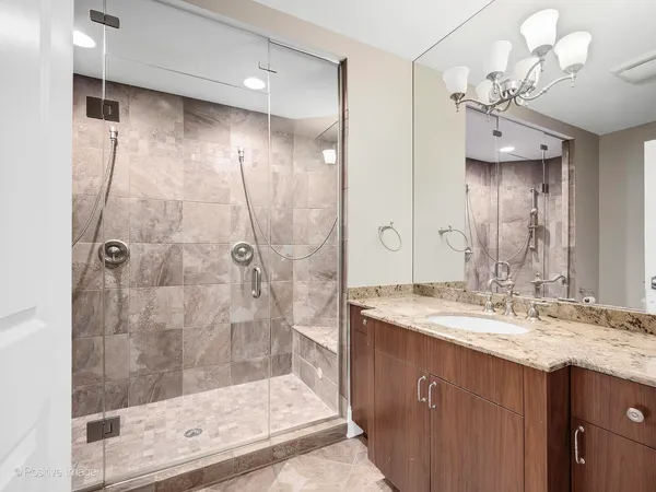 a bathroom with a granite countertop sink a mirror and shower
