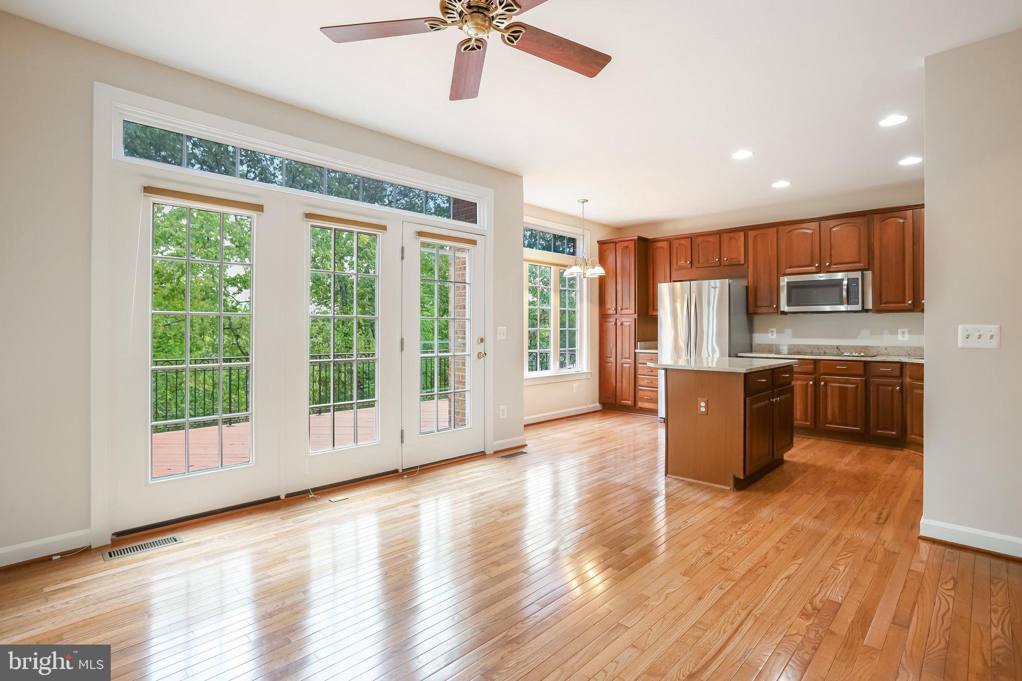 18546 Perdido Bay Terrace Leesburg, VA 20176 - Photo 12 of 57 a large kitchen with stainless steel appliances granite countertop a stove top oven a refrigerator a sink with a dining table and chairs with wooden floor