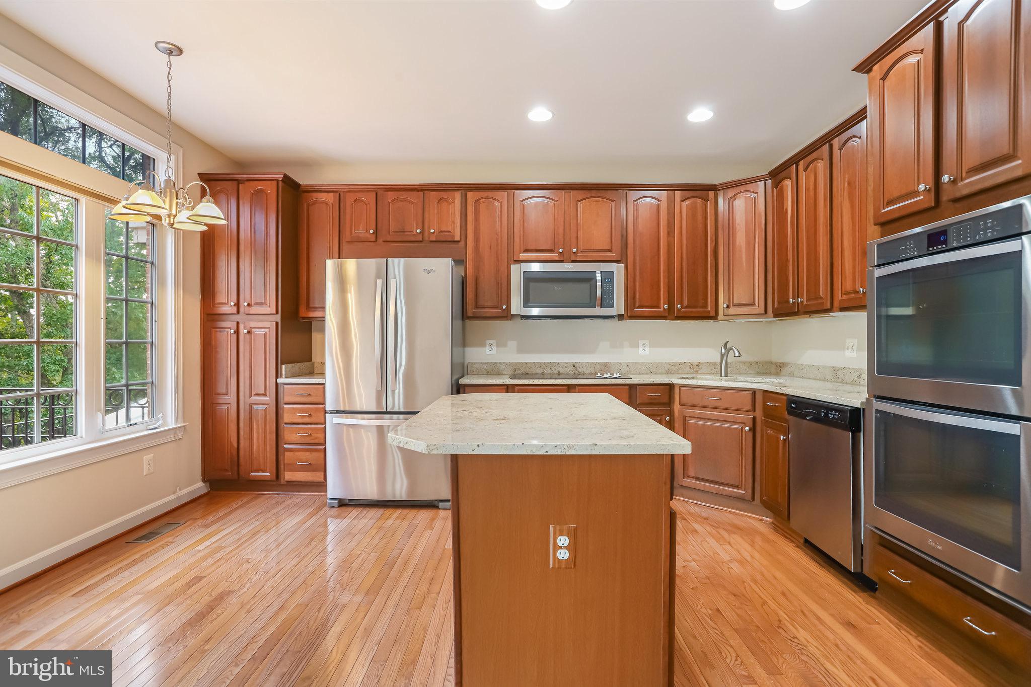 18546 Perdido Bay Terrace Leesburg, VA 20176 - Photo 17 of 57 a kitchen with kitchen island granite countertop wooden cabinets stainless steel appliances a sink and a large window