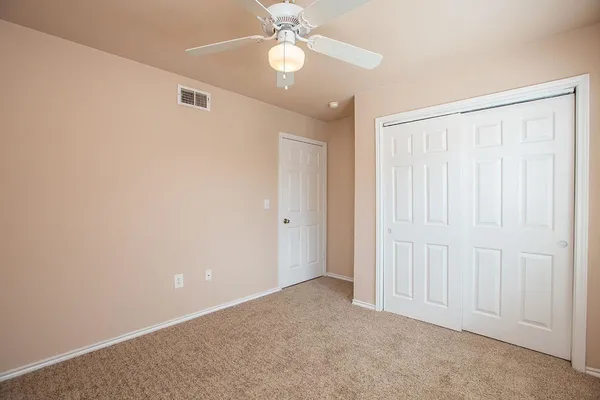an empty room with a ceiling fan and a window