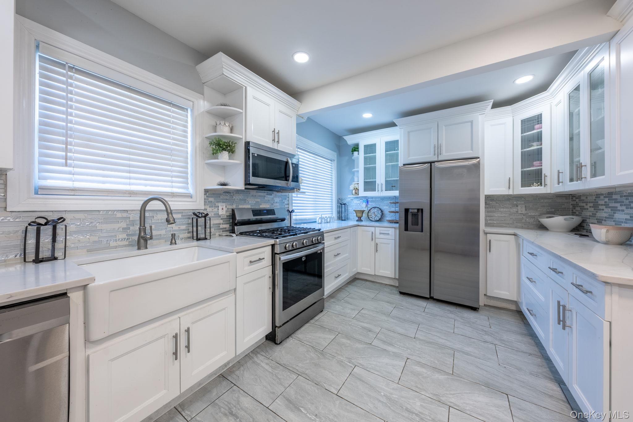 116-01 221st Street Queens, NY 11411 - Photo 13 of 19 Kitchen featuring white cabinetry, stainless steel appliances, open shelves, light stone countertops, and backsplash