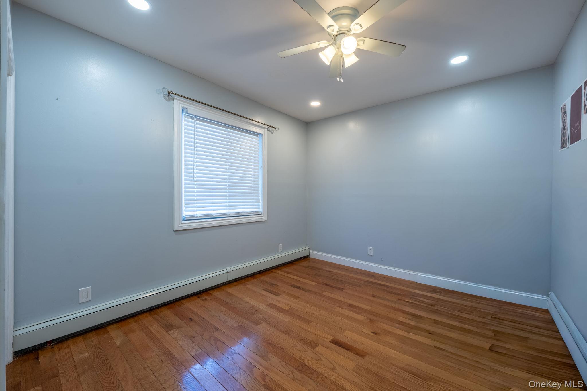 116-01 221st Street Queens, NY 11411 - Photo 15 of 19 Empty room featuring a baseboard radiator, a baseboard heating unit, hardwood / wood-style flooring, recessed lighting, and a ceiling fan