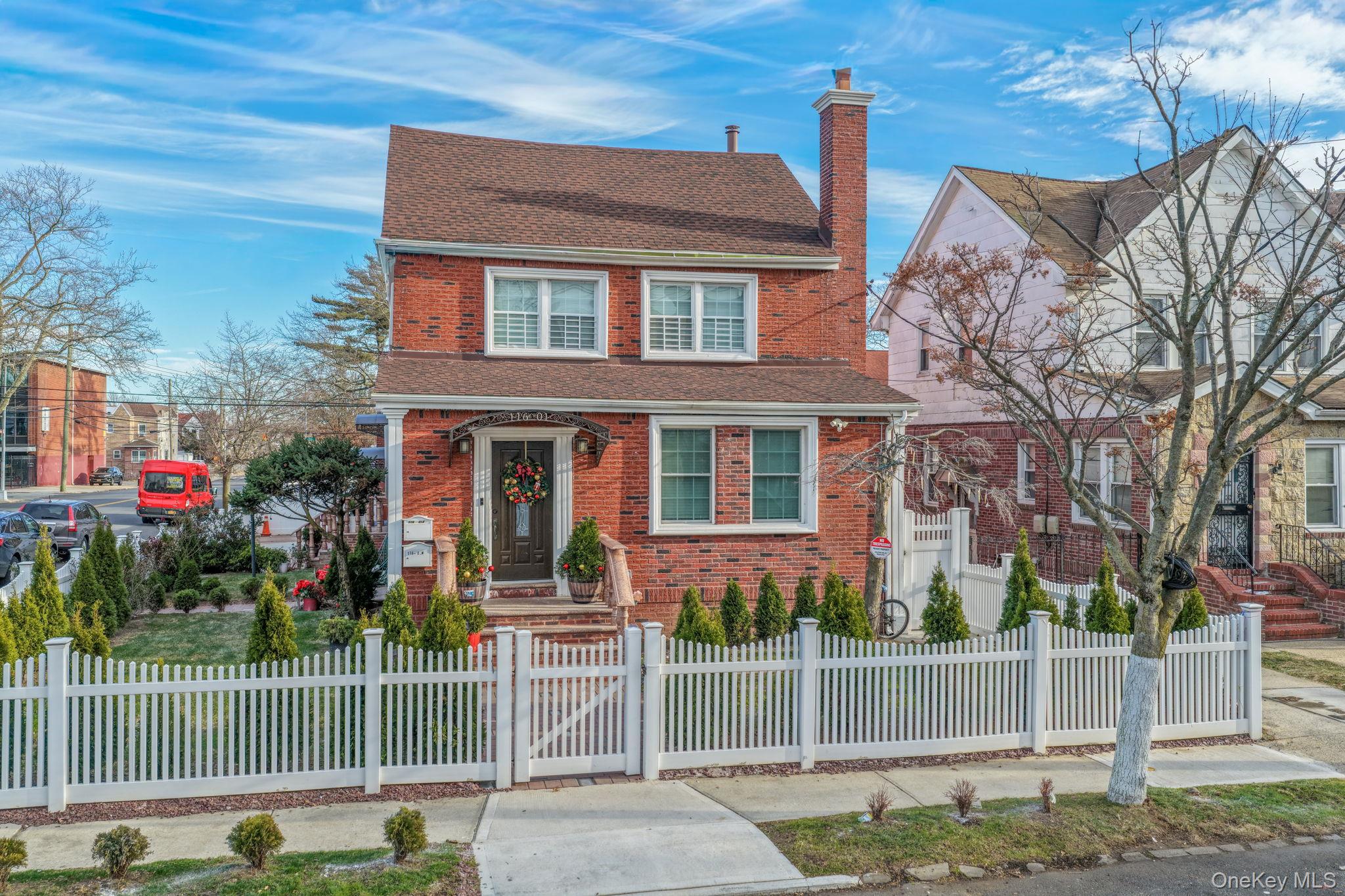 116-01 221st Street Queens, NY 11411 - Photo 2 of 19 View of front of house featuring a shingled roof, a gate, a chimney, brick siding, and a fenced front yard