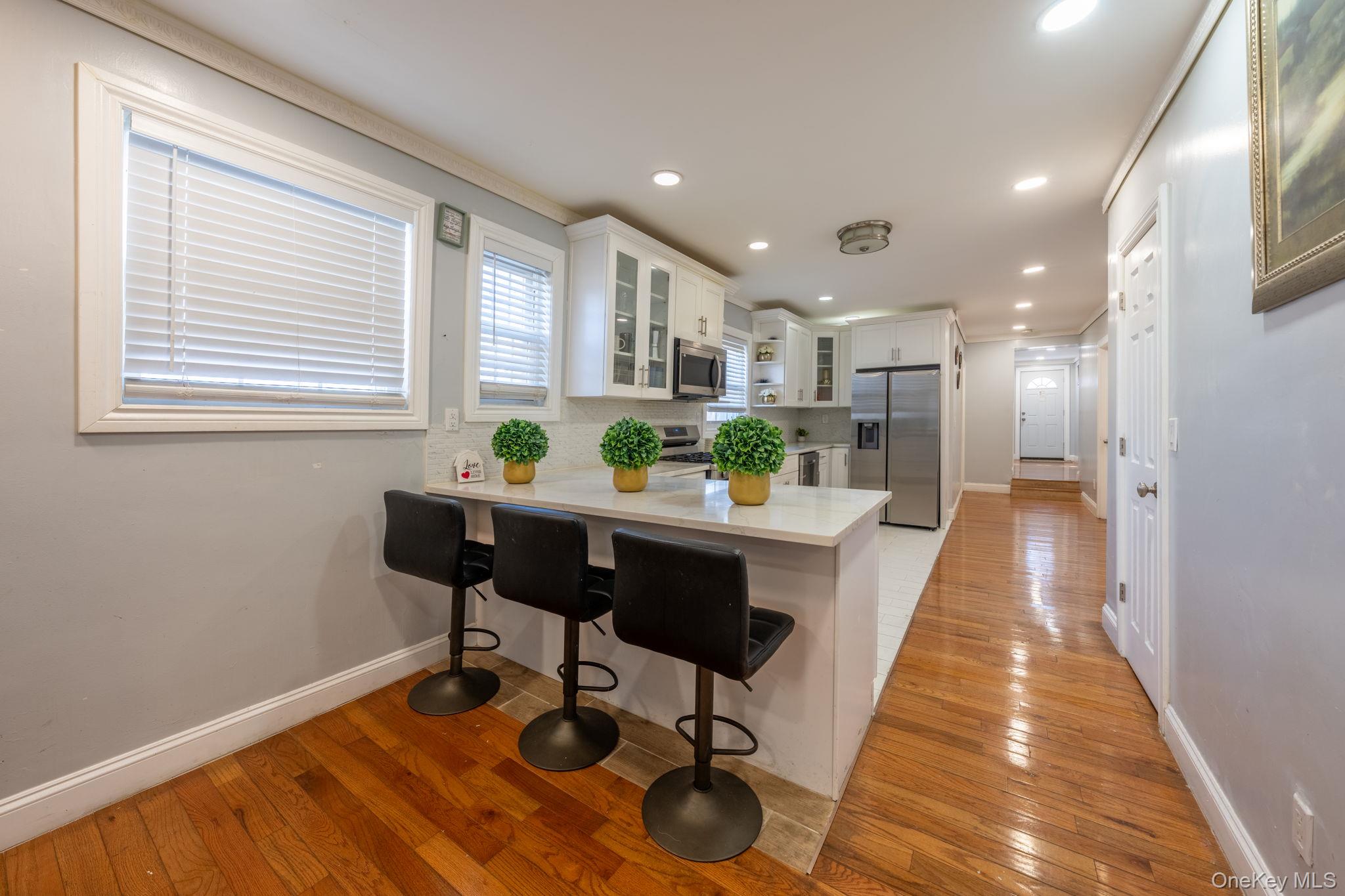116-01 221st Street Queens, NY 11411 - Photo 5 of 19 Kitchen featuring glass insert cabinets, appliances with stainless steel finishes, light wood-type flooring, white cabinetry, and recessed lighting