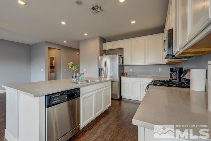 9405 Cape Drive Reno, NV 89506 - Photo 4 of 17 a kitchen with stainless steel appliances granite countertop a sink a stove a refrigerator and white cabinets with wooden floor