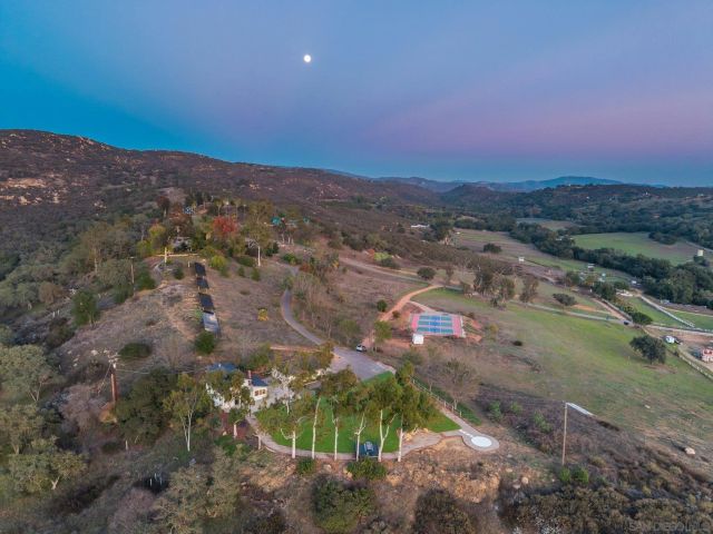 a front view of a house with a yard and mountain view in back