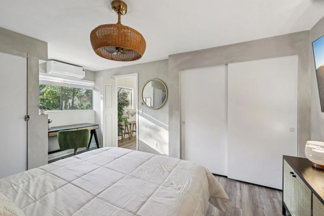 a bedroom with a bed lamp and a large window with wooden floor