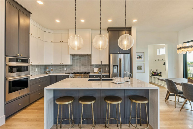 2458 West Aurora Avenue, Unit 287 Mapleton, UT 84664 - Photo 9 of 24 Kitchen featuring light stone countertops, hanging light fixtures, tasteful backsplash, a large island, and a breakfast bar area