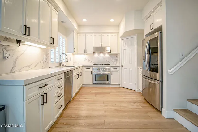 a large kitchen with stainless steel appliances double vanity and a refrigerator