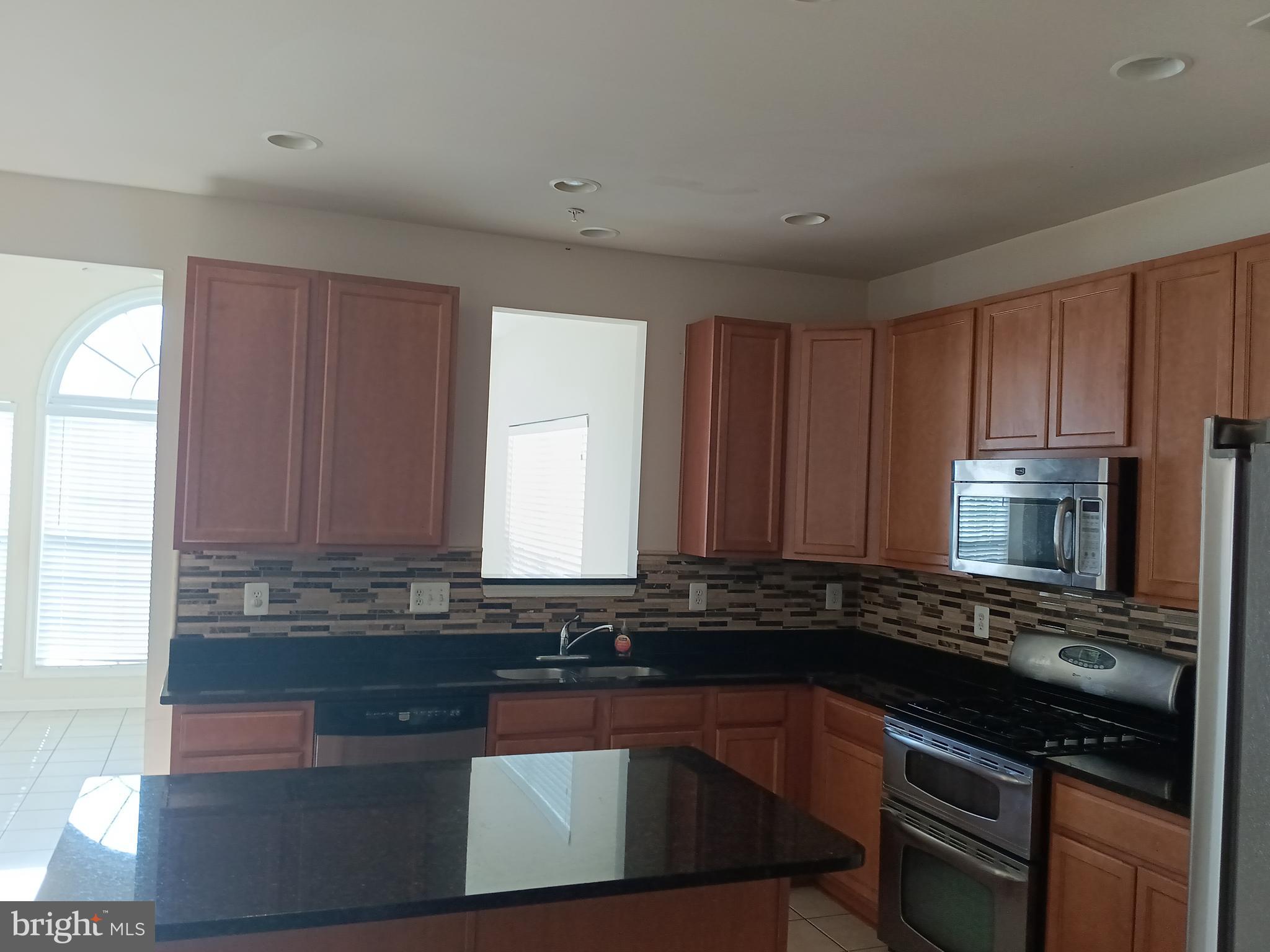 9707 Risen Star Drive Upper Marlboro, MD 20772 - Photo 17 of 35 a kitchen with granite countertop a sink stove and microwave