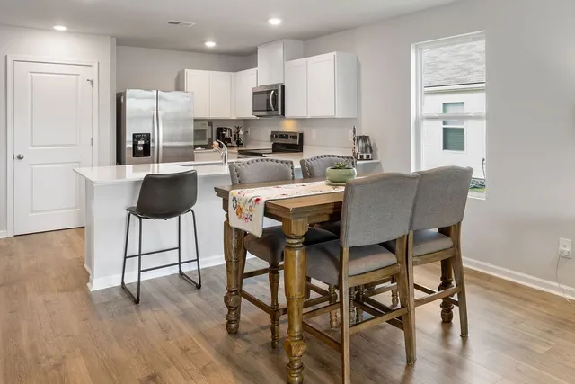 a kitchen with stainless steel appliances kitchen island granite countertop a dining table chairs and view living room