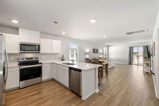 a kitchen with stainless steel appliances kitchen island granite countertop a stove top oven a sink a counter space and cabinets