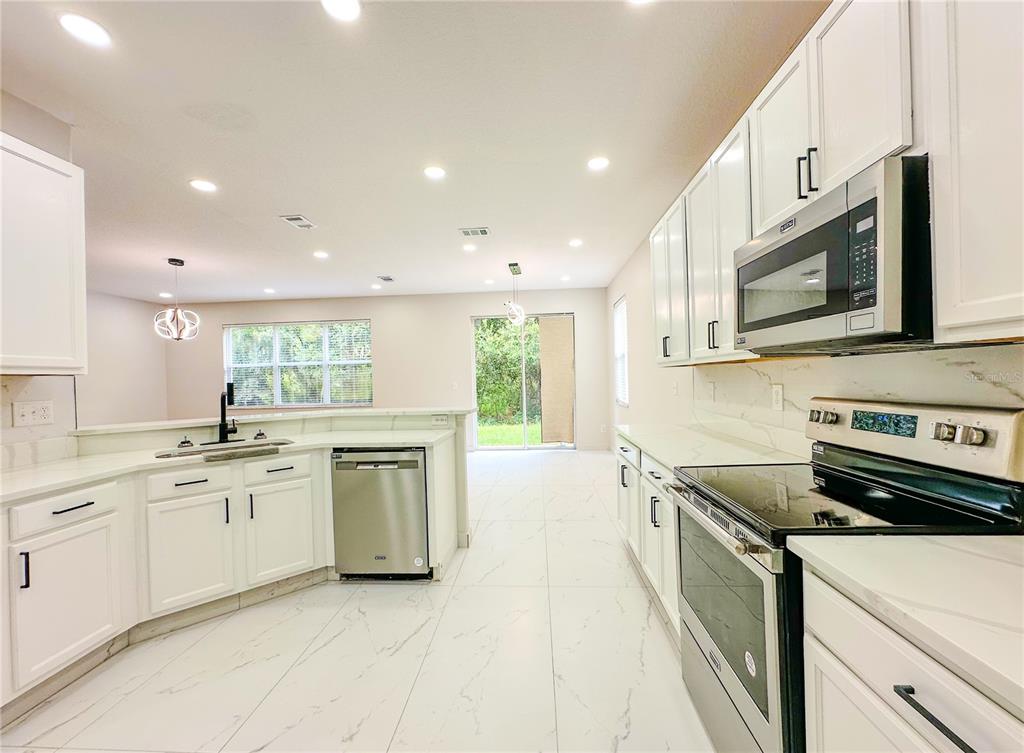 7322 Bridgeview Drive Wesley Chapel, FL 33545 - Photo 17 of 75 a kitchen with stainless steel appliances granite countertop a stove top oven a sink a microwave and a refrigerator