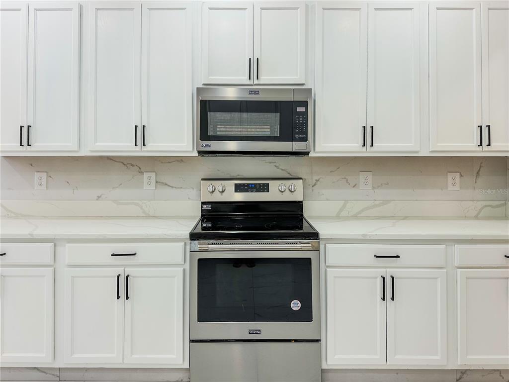 7322 Bridgeview Drive Wesley Chapel, FL 33545 - Photo 21 of 75 a kitchen with white cabinets and stainless steel appliances
