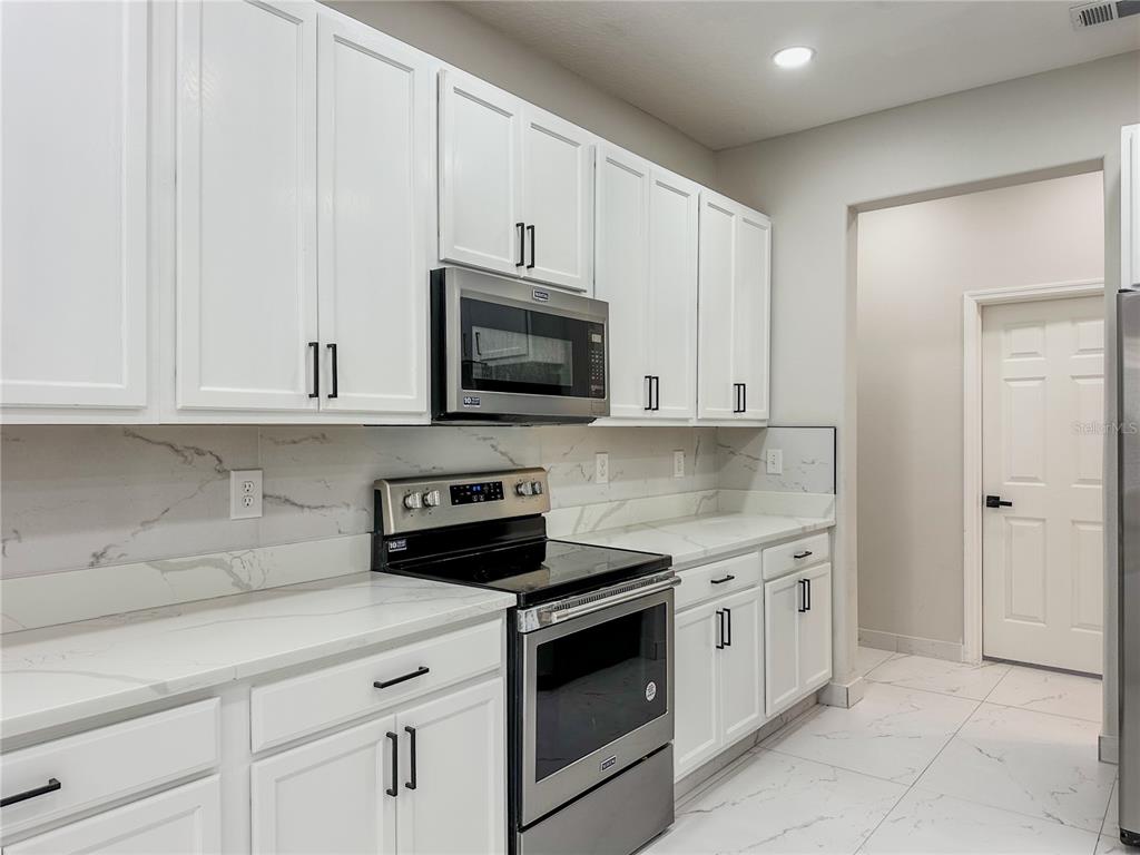 7322 Bridgeview Drive Wesley Chapel, FL 33545 - Photo 22 of 75 a kitchen with white cabinets and white appliances