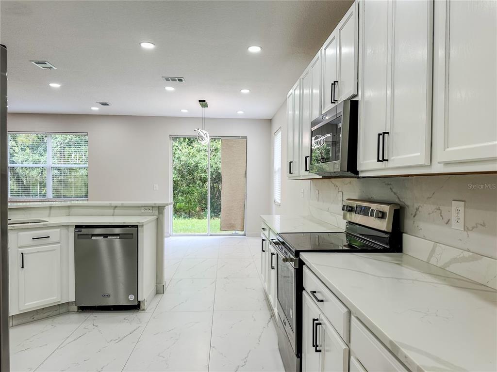 7322 Bridgeview Drive Wesley Chapel, FL 33545 - Photo 23 of 75 a kitchen with stainless steel appliances granite countertop a stove a sink and a microwave