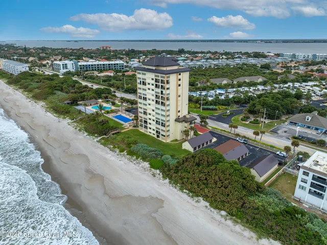 an aerial view of a city with lots of residential buildings ocean and mountain view in back