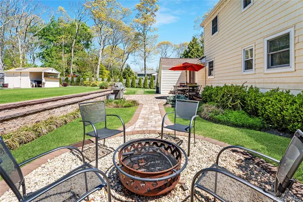 a view of a patio with table and chairs potted plants and a large tree
