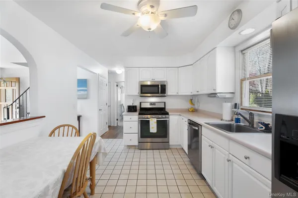 a kitchen with stainless steel appliances granite countertop a sink dishwasher a stove top oven a refrigerator with island and chairs