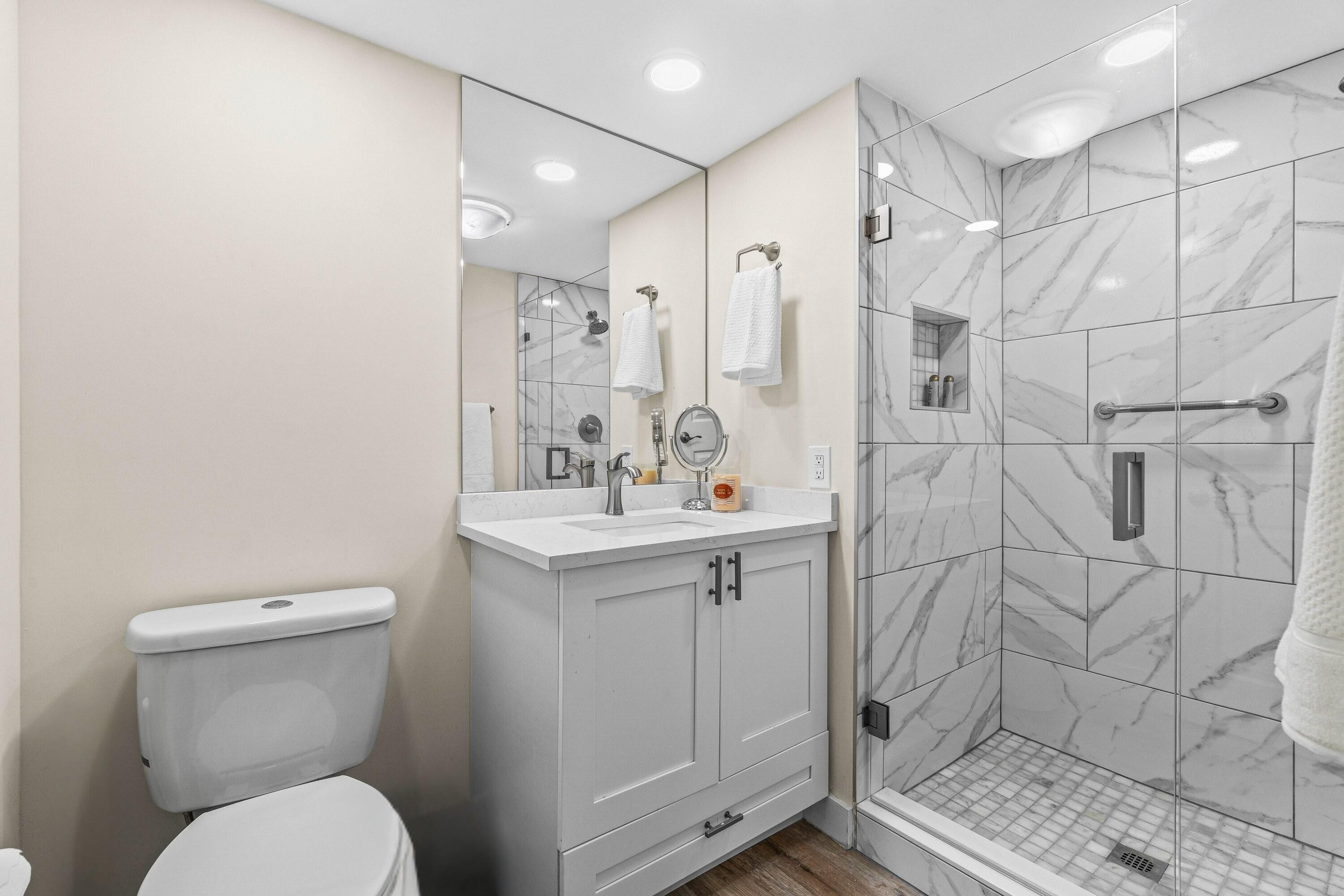 18 Stratford Drive, Unit E Boynton Beach, FL 33436 - Photo 13 of 49 a bathroom with a granite countertop toilet sink shower and mirror