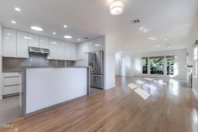 a view of kitchen with stainless steel appliances kitchen island wooden floor granite counter tops and a stove top oven
