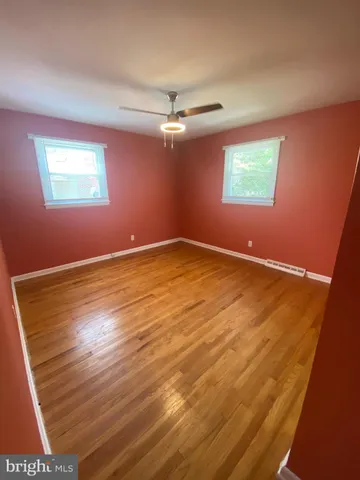 an empty room with wooden floor chandelier fan and windows