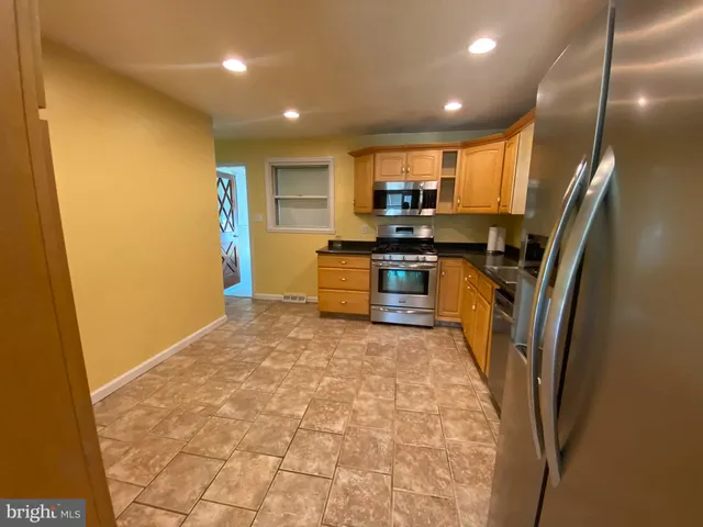a large kitchen with stainless steel appliances a refrigerator and a stove top oven