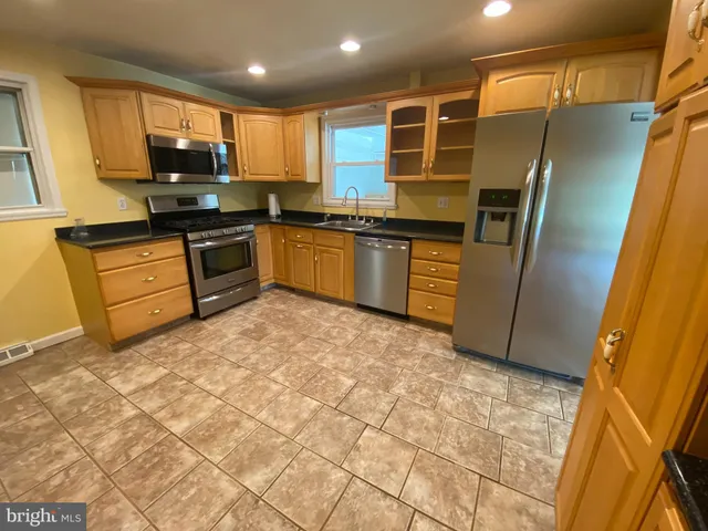 a kitchen with granite countertop a refrigerator and wooden cabinets
