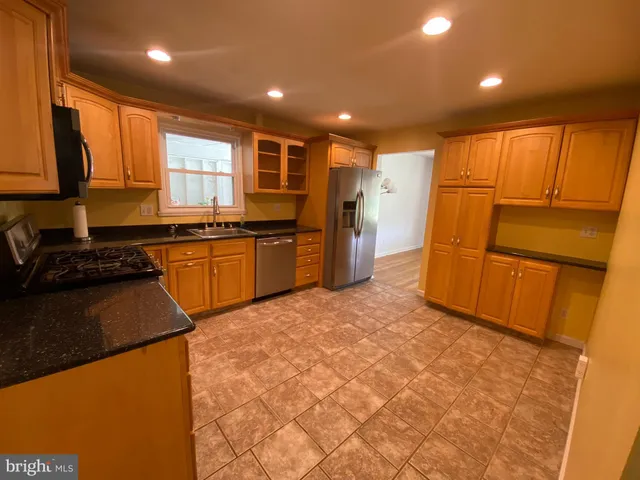 a kitchen with stainless steel appliances granite countertop a refrigerator a sink dishwasher and a stove