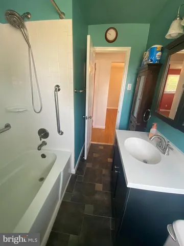 a bathroom with a tub sink and mirror