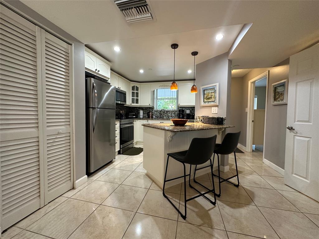 17801 North Bay Road, Unit 212 Sunny Isles Beach, FL 33160 - Photo 11 of 48 a kitchen with stainless steel appliances kitchen island granite countertop a refrigerator and cabinets