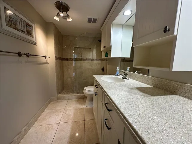 a bathroom with a granite countertop sink a toilet and a mirror