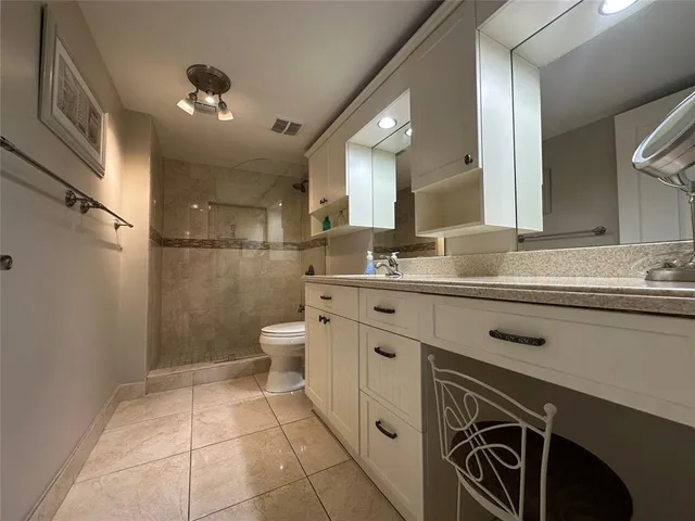 a spacious bathroom with a sink a toilet a mirror and shower