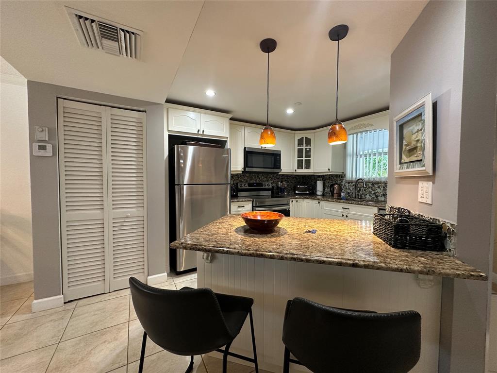 17801 North Bay Road, Unit 212 Sunny Isles Beach, FL 33160 - Photo 7 of 48 a kitchen with stainless steel appliances granite countertop a refrigerator a sink a stove a dining table and chairs