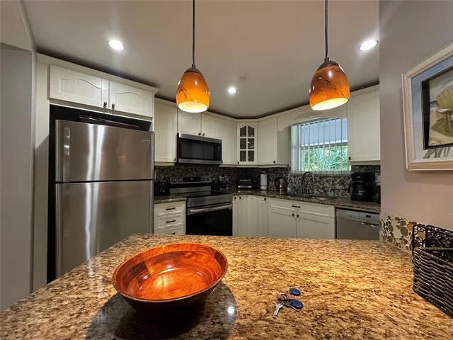 a kitchen with stainless steel appliances granite countertop a stove a refrigerator and a wooden floor