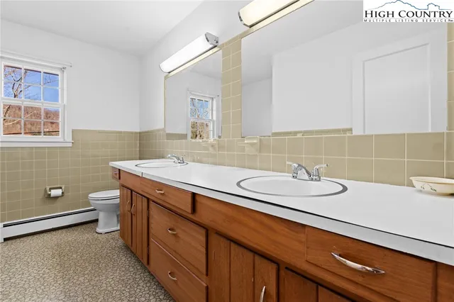 a bathroom with a granite countertop double vanity sink a mirror and a toilet