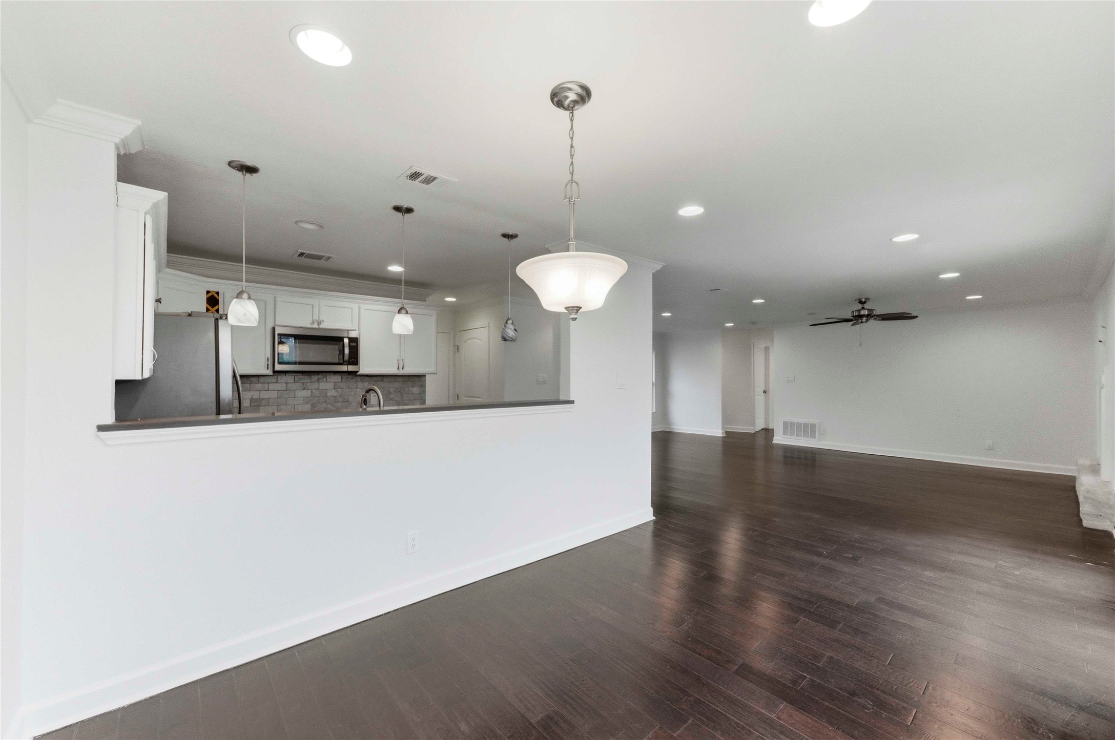 1909 Crooked Lane Austin, TX 78741 - Photo 12 of 25 Kitchen featuring dark wood finished floors, white cabinetry, a ceiling fan, pendant lighting, and recessed lighting