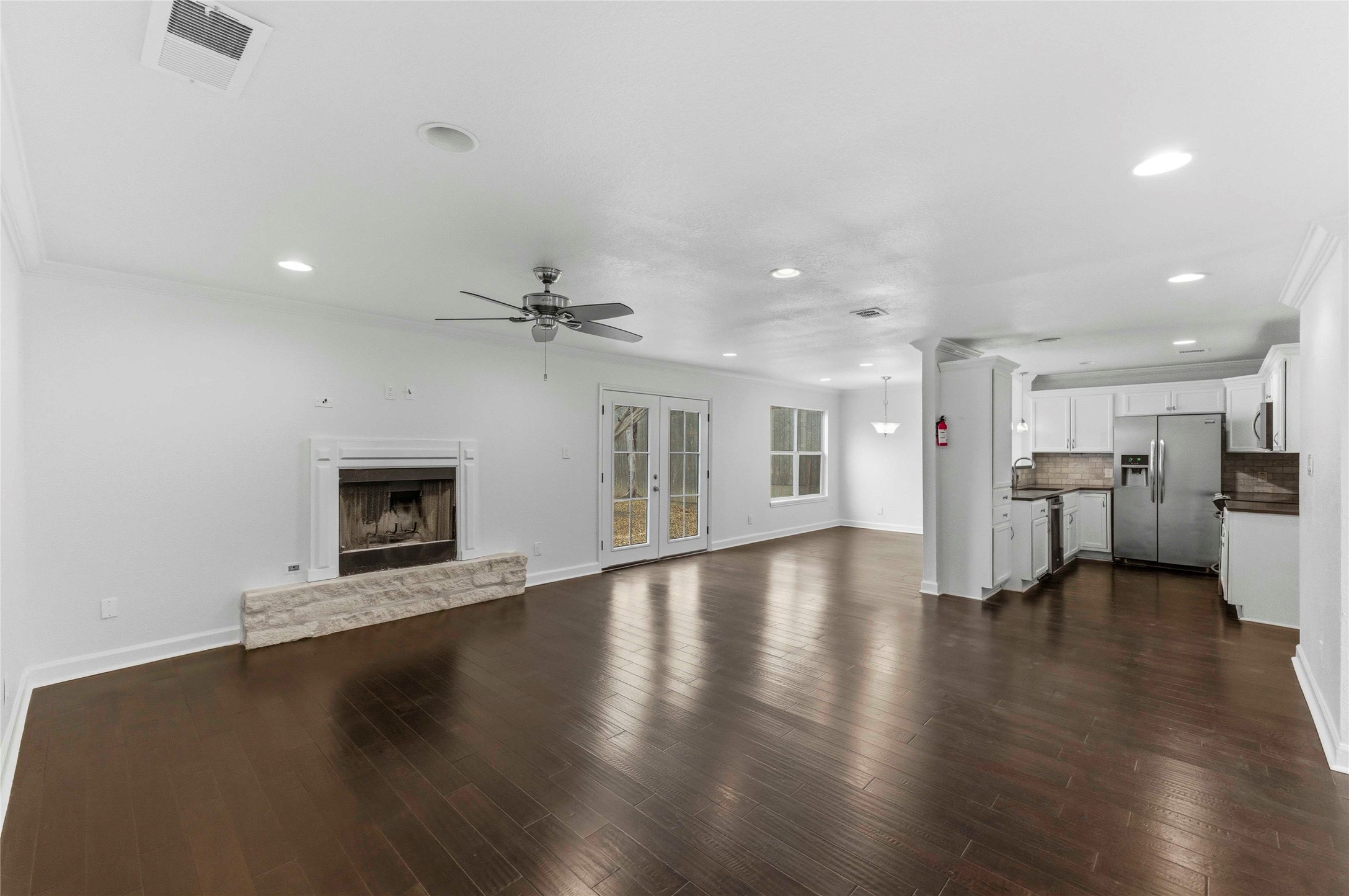 1909 Crooked Lane Austin, TX 78741 - Photo 4 of 25 Unfurnished living room featuring recessed lighting, dark wood finished floors, a fireplace, french doors, and a ceiling fan