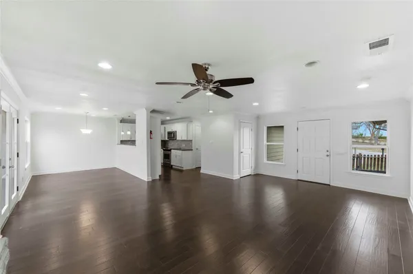 an empty room with wooden floor and a ceiling fan