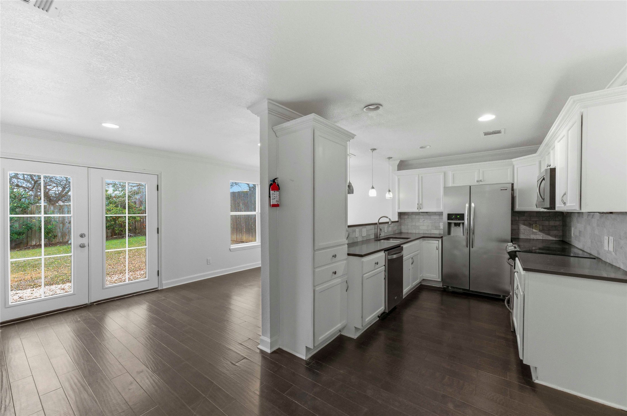 1909 Crooked Lane Austin, TX 78741 - Photo 7 of 25 Kitchen with white cabinets, dark countertops, pendant lighting, stainless steel appliances, and dark wood-type flooring