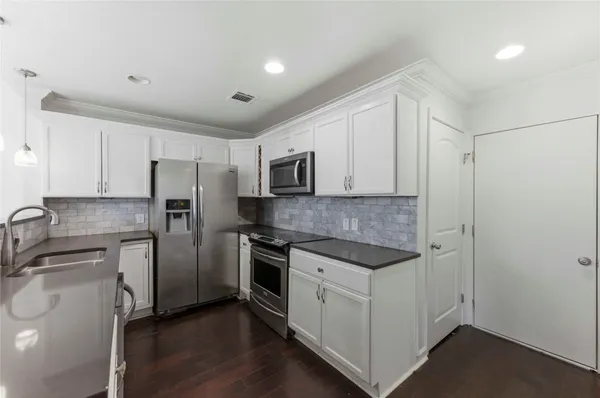 a kitchen with white cabinets and stainless steel appliances