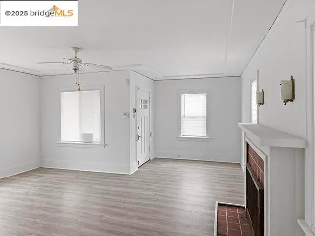 a view of an empty room with a window and wooden floor