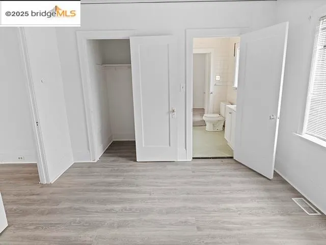 a view of an empty room with wooden floor and a bathroom