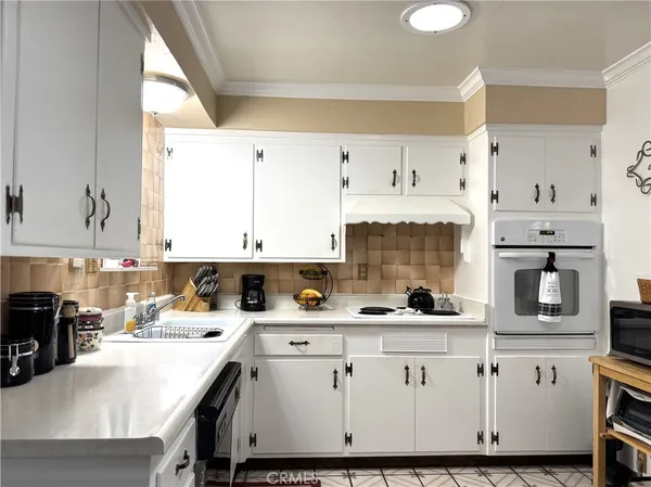 a kitchen with stainless steel appliances white cabinets a sink a stove a refrigerator and island with wooden floor